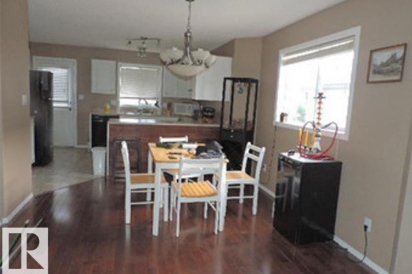 Dining area with a wood table and chairs, adjacent to the kitchen. - 1318 8 Av, Cold Lake