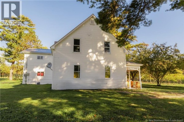 Back and side view of a white farmhouse with multiple windows and a small covered porch. - 1319 Aroostook Rd., Perth Andover