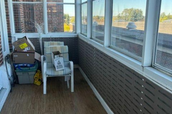 Sunroom with two chairs, boxes, and screened windows. - 132 - 200 Wende Avenue, Timmins