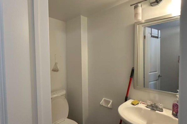 A half bathroom with a white toilet, sink, and mirror, next to a doorway. - 132 - 322 John Street, Markham