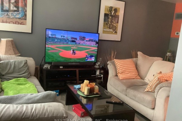Living room with two sofas, a coffee table, and a large television. - 132 - 70 Absolute Avenue, Mississauga