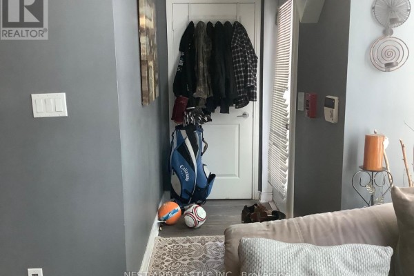 Hallway with coats hanging on the wall, a golf bag, and a door. - 132 - 70 Absolute Avenue, Mississauga