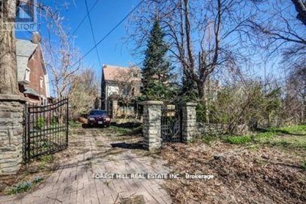 Overgrown driveway leading to a stone gate and a parked car. - 132 Blythwood Road, Toronto