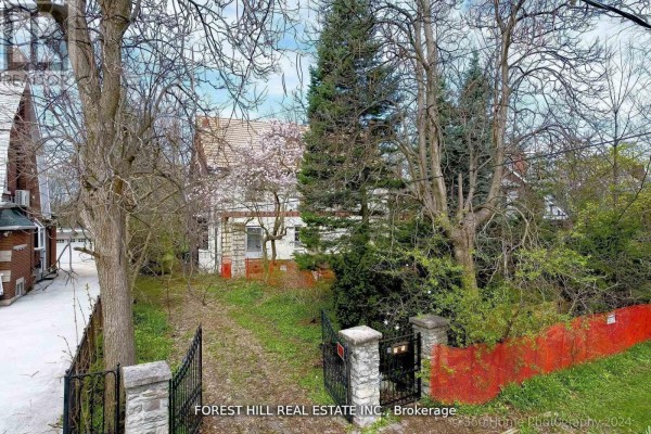 Side view of the house showing overgrown vegetation and a tree in front. - 132 Blythwood Road, Toronto