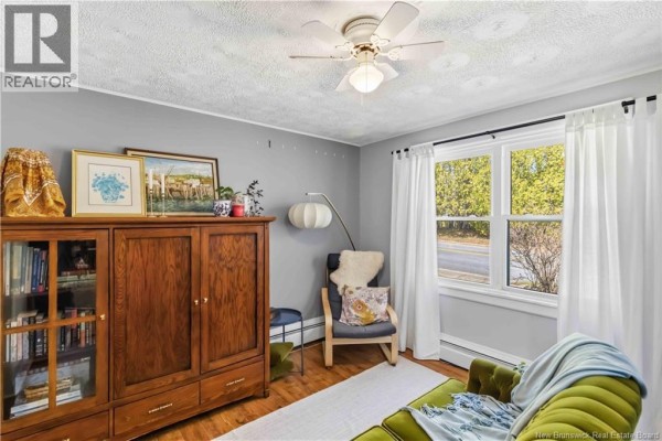 Sunroom with a small dining table, chairs, and large windows overlooking a road. - 132 Golf Club Road, Fredericton