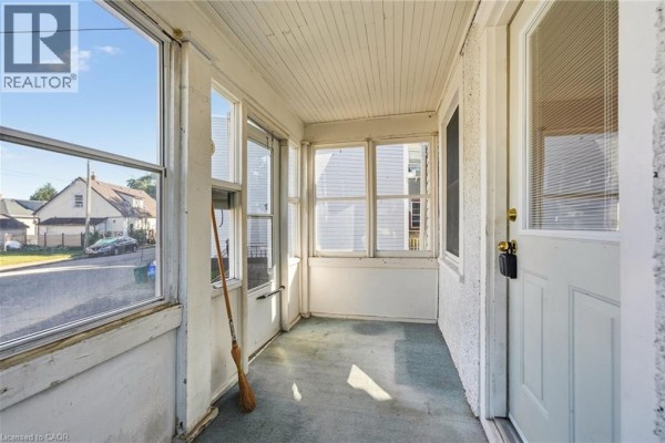 Inside the enclosed sunroom, looking out at the street through large windows. - 132 Grass Avenue, St  Catharines