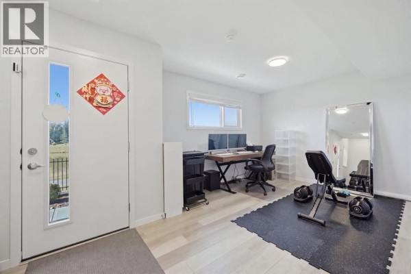 Interior room with white walls, a desk with computers, and exercise equipment. - 132 Harvest Grove Walk Nw, Calgary
