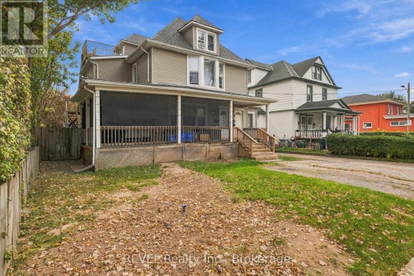 Rear exterior of the multi-family home with a lawn, fence, and attached garage. - 132 Hellems Avenue, Welland