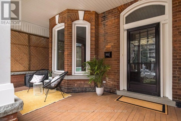 Covered front porch with two chairs, a yellow rug, and a bay window. - 132 Herkimer Street, Hamilton