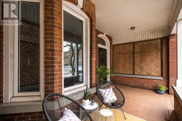 View of the front porch with seating, brick walls, and latticework screens. - 132 Herkimer Street, Hamilton
