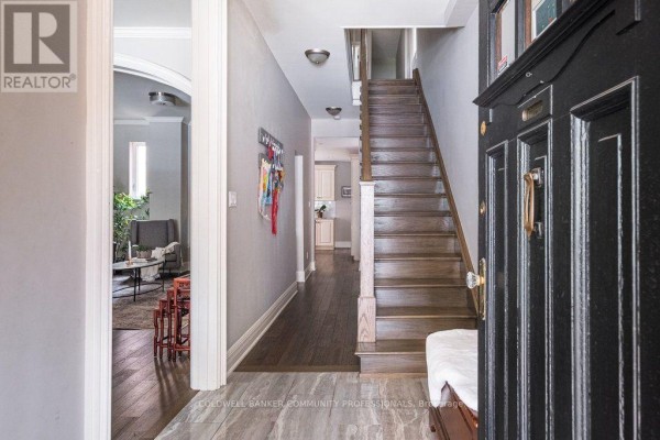 Interior view of a hallway with a staircase, hardwood floors, and an open doorway. - 132 Herkimer Street, Hamilton