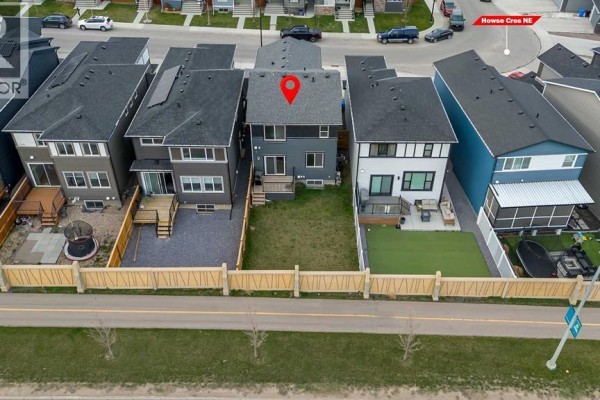 Aerial view of the backyards of three houses on a street with a fence along a road. - 132 Howse Crescent Ne, Calgary