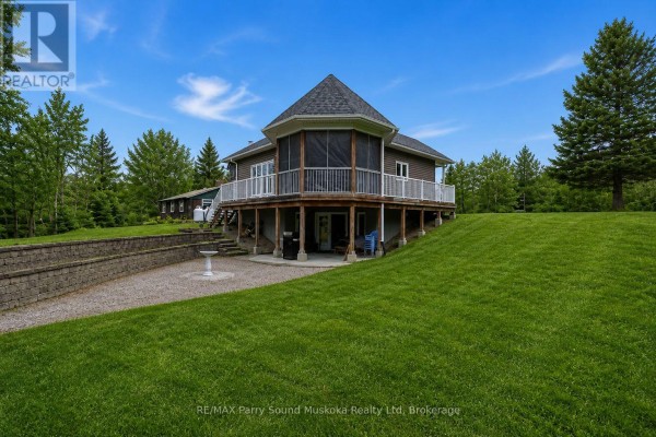 Two rustic wooden barns situated in a grassy field with scattered evergreen trees under a blue sky. - 132 Lawson Drive, Kearney