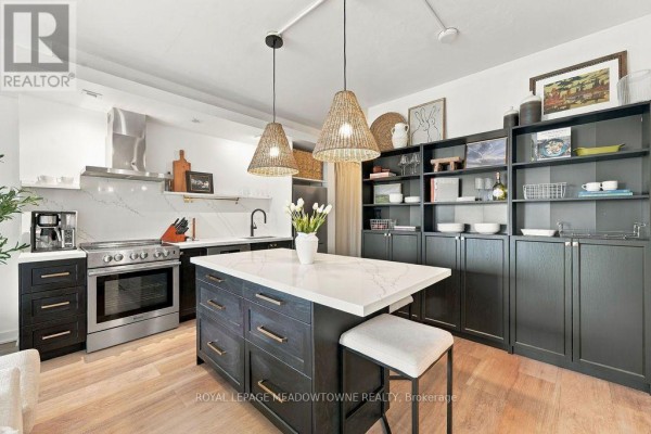 Kitchen area with dark cabinetry, a large island with seating, and floor-to-ceiling storage. - 1321 - 165 Legion Road N, Toronto