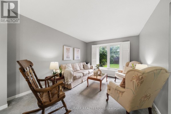 Dining room with a table set for six, antique buffet, and adjacent living room. - 1322 Redwood Lane, Pickering
