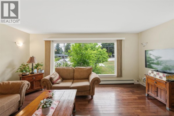 Backyard view showing green grass, wooden fence, and part of the house. - 1322 Ridgedale Avenue, Penticton