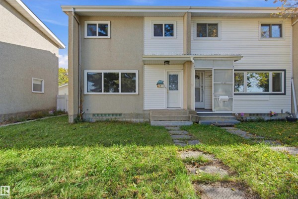 Exterior view of the townhouse with a grassy lawn and a stone pathway. - 13223 85 St Nw, Edmonton