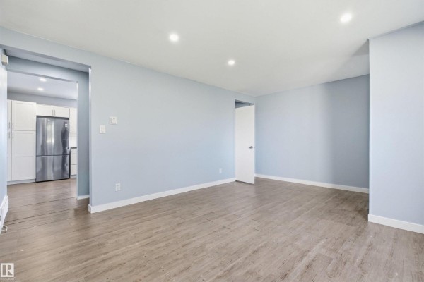 Open concept living area with light blue walls and a doorway to the kitchen. - 13223 85 St Nw, Edmonton