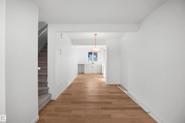 Open-concept living area with wood floors, stairs, and a small wet bar. - 1324 9 St Nw, Edmonton