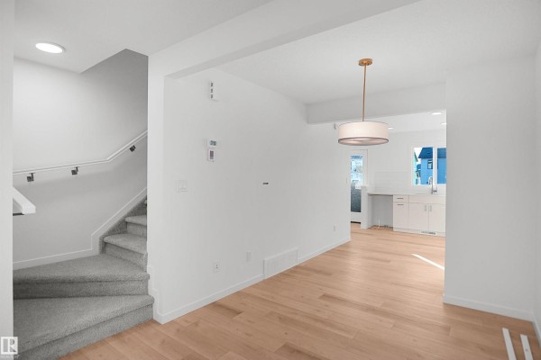 Living area with wood floors, a large window, and a view of construction. - 1324 9 St Nw, Edmonton