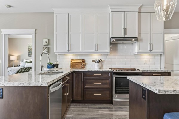 Kitchen with white cabinets, stainless steel range, and granite countertops, showing an adjacent bedroom. - 1324 Stromdahl Place, Mt Woodside, Agassiz