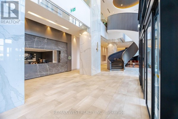 Modern building lobby with marble walls, a spiral staircase, and tiled floors. - 1327 - 5 Mabelle Avenue, Toronto