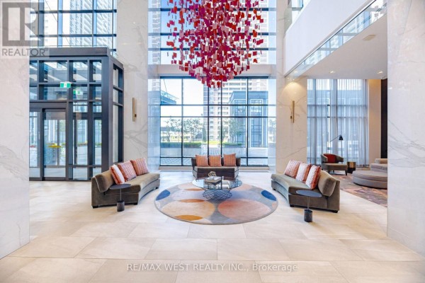 Spacious building lobby with curved sofas, a circular rug, and a large red sculpture. - 1327 - 5 Mabelle Avenue, Toronto