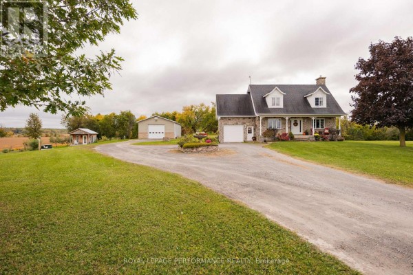 Wide view of the stone house, garage, and driveway from the curved lawn. - 1327 County Road 34 Road, North Glengarry