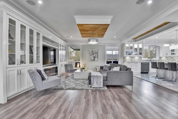 Spacious living room with grey sectional sofa, large white coffee table, and fireplace. - 13291 Melville Place, Surrey
