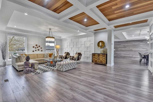 Large living room with L-shaped sofa, patterned chairs, coffered wood ceiling, and wood floors. - 13291 Melville Place, Surrey