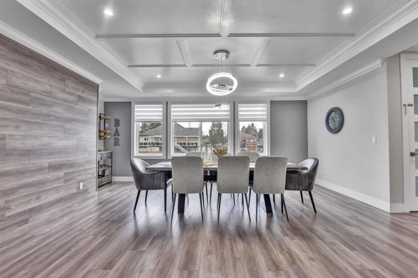 Modern kitchen with white cabinets, grey island with seating, marble countertops, and pendant lighting. - 13291 Melville Place, Surrey