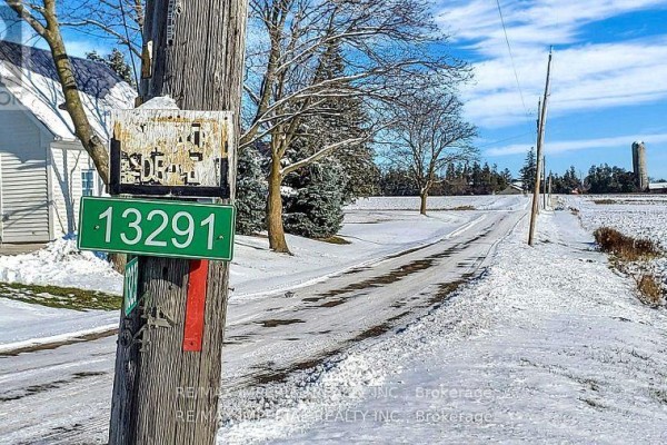 Snowy rural road with a wooden pole displaying street signs and a silo in distance. - 13291 Warden Avenue, Whitchurch Stouffville