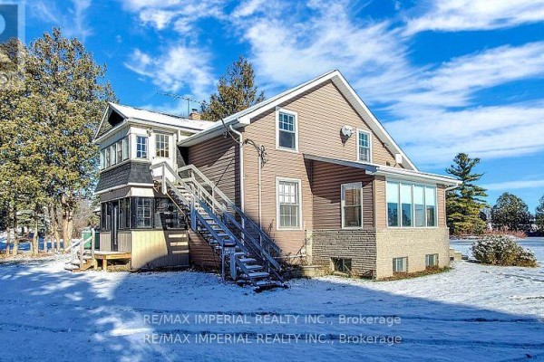 Side view of a two-story house with a sunroom and outdoor stairs in winter. - 13291 Warden Avenue, Whitchurch Stouffville