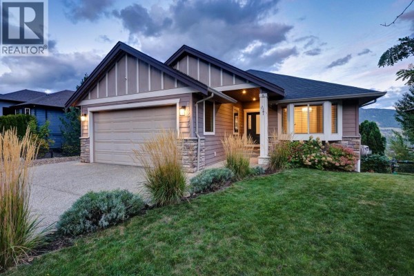 Evening view of the tan house with beige garage door and stone accents. - 13296 Lake Hill Drive, Lake Country
