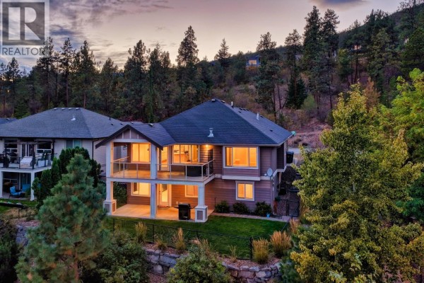 Rear view of the tan house with multiple balconies and large windows. - 13296 Lake Hill Drive, Lake Country