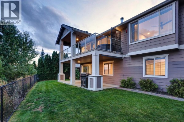 Side view of the house showing a fenced backyard and covered patio. - 13296 Lake Hill Drive, Lake Country