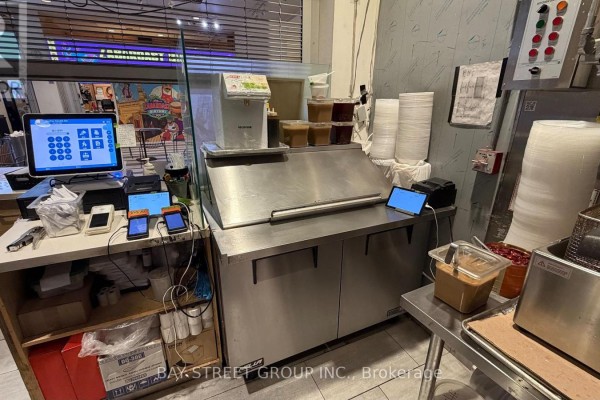 Commercial kitchen counter with stainless steel ice machine, POS system, card readers, and containers. - 133 - 4750 Yonge Street, Toronto