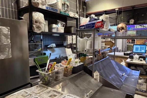 Commercial kitchen shelving with various food service supplies and containers, next to a counter. - 133 - 4750 Yonge Street, Toronto