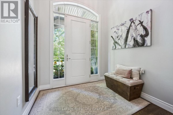 Home entrance foyer with a white double door, arched transom window, tiled floor, and artwork. - 133 Cooks Mill Road, Puslinch