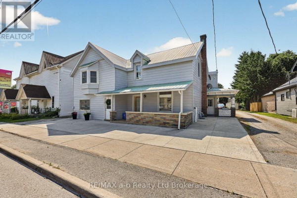 Side view of the commercial building showing the entrance, porch, and driveway on the right. - 133 Dundas Street, Zorra