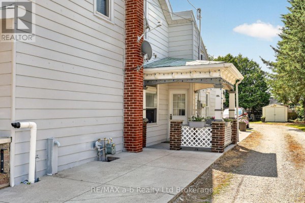 Close-up of the side porch with brick accents, white lattice, and a doorway. - 133 Dundas Street, Zorra