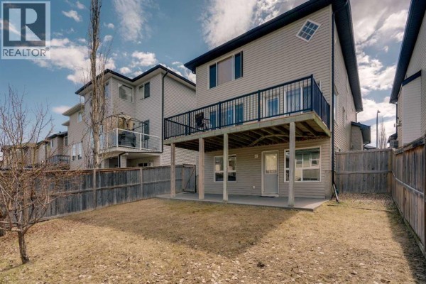 View of the backyard from the rear of the house, showing a deck, fence, and lawn. - 133 Everwoods Close Sw, Calgary