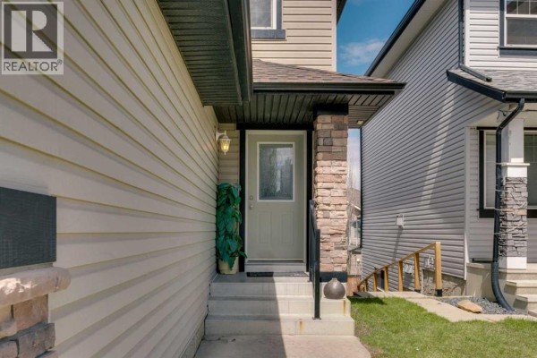Close-up of the front door entrance with steps, stone accents, and exterior lighting. - 133 Everwoods Close Sw, Calgary