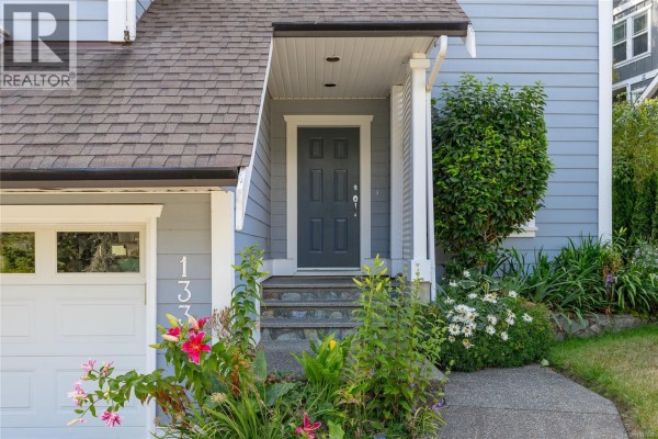 Close-up of the front entrance of a light blue house with a dark grey door, steps, and flowers. - 133 Gibraltar Bay Dr, View Royal