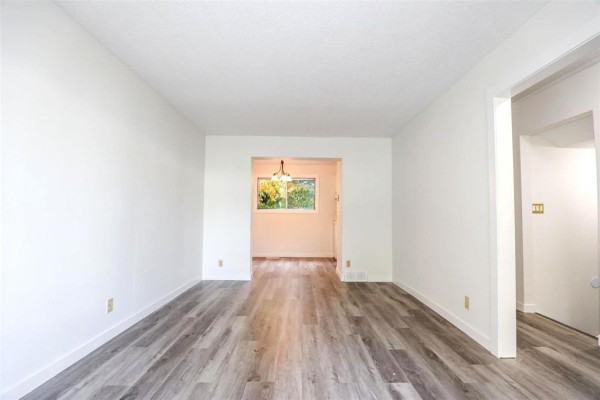 Interior view of the living room showing an opening to a dining area and a closet. - 133 Lake Ridge Road, Winnipeg
