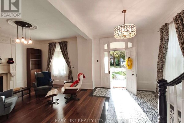 Living room with hardwood floors, white walls, gray armchairs, and a white armchair with ottoman. - 133 Main Street, Markham