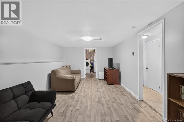 Another view of the basement living area, showing a doorway to a laundry room. - 133 Willis Street, Fredericton