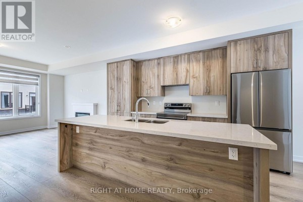 Modern kitchen with light wood cabinetry, quartz island, stainless steel appliances, and island sink. - 1330 Shevchenko Boulevard, Oakville