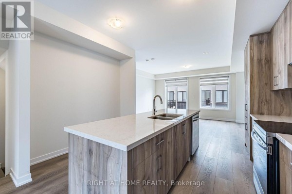 Open concept kitchen and living area with island, light wood cabinets, stainless steel appliances, and fireplace. - 1330 Shevchenko Boulevard, Oakville