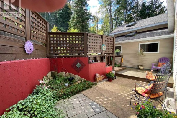 View of a backyard patio with wooden decks, lattice screens, stairs, and seating areas. - 13302 15 Avenue, Blairmore